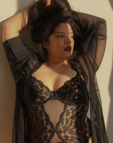 Una mujer de talla grande vistiendo un body de encaje negro y una bata transparente con luz natural 