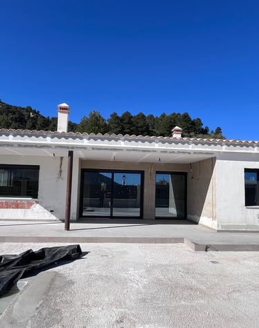 Villa moderne blanche récemment construite, avec baies vitrées coulissantes sous un ciel bleu dégagé