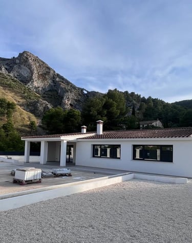 Villa moderne blanche avec toit en terre cuite, nichée au cœur de montagnes pittoresques