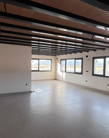 Pièce moderne en open space en cours de construction, avec poutres métalliques apparentes au plafond