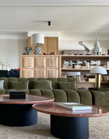 Contemporary lounge at Villa La Gratitud with velvet sofas, round marble tables, and bookshelves.