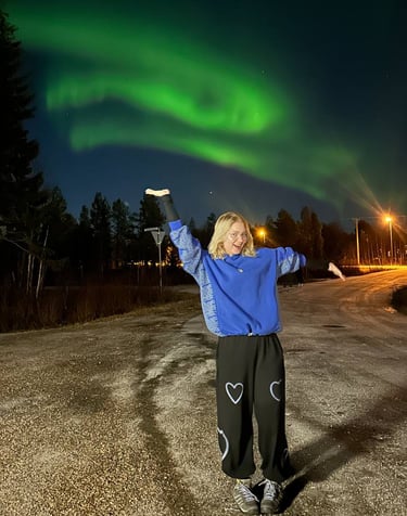 a woman standing under the northern lights