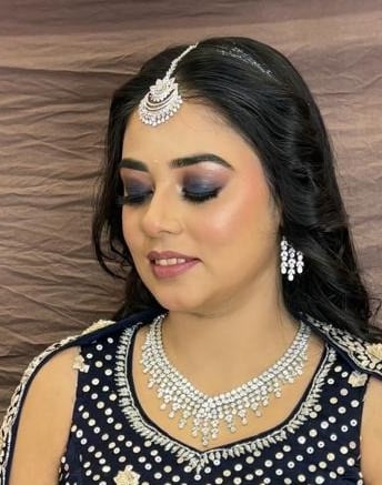 Indian bride-to-be in navy blue lehenga with smokey eye engagement makeup, diamond jewelry, loose cu