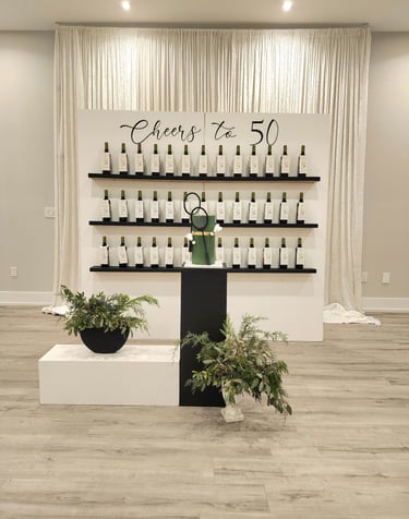 a backdrop display of wine bottles as a favor wall for a 50th birthday celebration