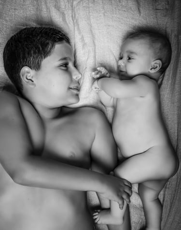 "Un retrato de familia en blanco y negro, hermano mayor y bebé acostados"