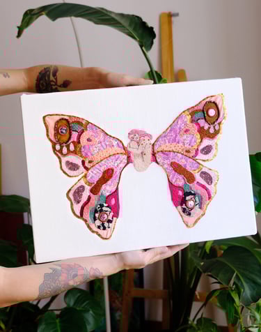 a person holding a butterfly - shaped canvas with a embroidered butterfly