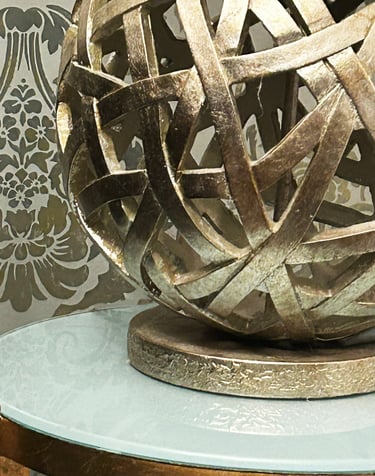 intricately designed gold metal lamp on a gold leaf and glass table