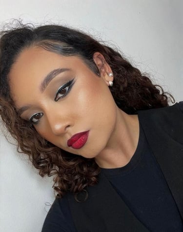 Mujer con cabello rizado que luce un atrevido lápiz labial rojo y un dramático maquillaje 