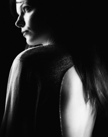 A moody black and white film grain portrait of a woman's profile with dramatic rim lighting.