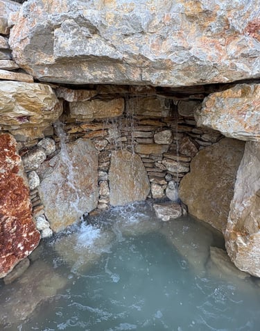 Handcrafted grotto cave under waterfall with limestone & quartzite for natural pool | Aqua Vitae