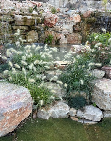 Natural pool wonderland with waterfalls, cave, stone benches & whimsical plantings | Aqua Vitae