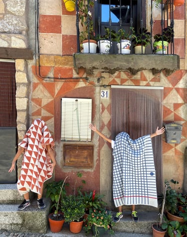 two people covered by blankets standing in front of a building