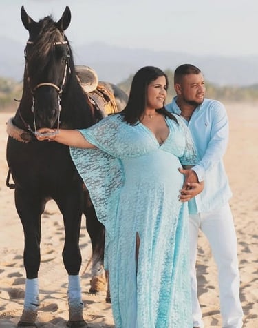 una mujer embarazada con su esposo y un caballo en la playa