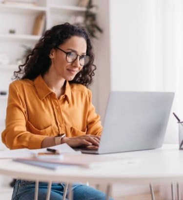 a woman sitting at a table with a laptop computer