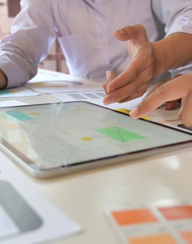 Dizajneri i projektni menadžeri analiziraju wireframe aplikacije na tabletu – primena Agile metodolo