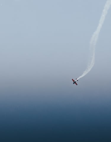 a plane flying in the sky with smoke coming out of it