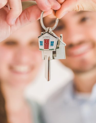 happy couple holding keys to a house after reading the guidebook created your neighbourhood surveyor