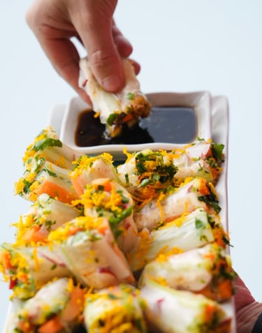 a person holding a plate with food and dipping sauce