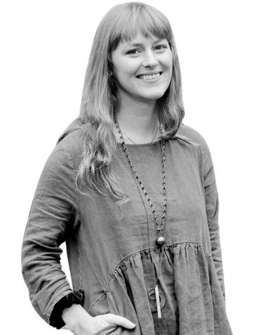 A picture of a woman standing. She is smiling.