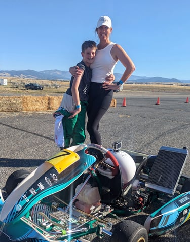 a woman and a boy are standing next to a race car