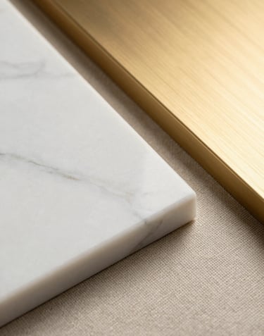 Close-up of premium interior materials: a piece of polished white marble, textured beige linen, and a sample of brushed gold metal. High-contrast lighting.