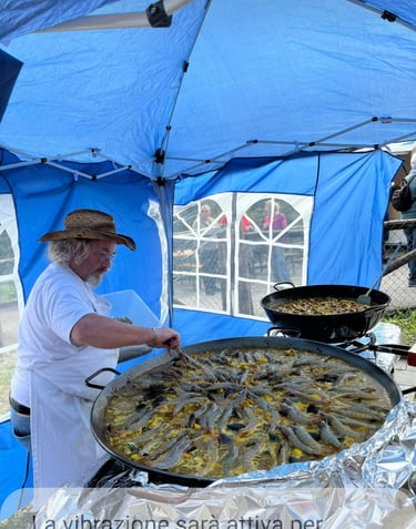 a man in a white shirt and a blue umbrella, paella, pranzo in compagnia Menzonio