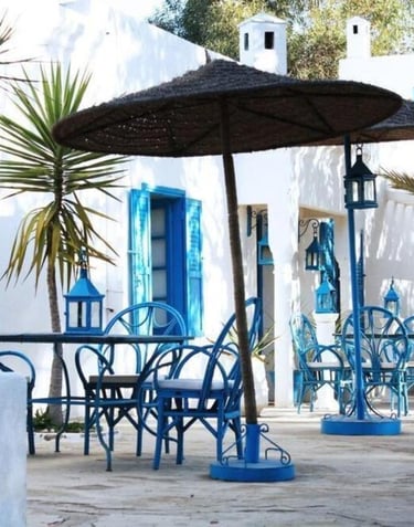 a table with chairs and umbrellas in front of a white building