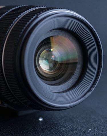 A sharp, detailed close-up of a premium camera lens front element, showing intricate glass coatings and light refraction. The style is professional and clean, using a dark blue-gray palette.