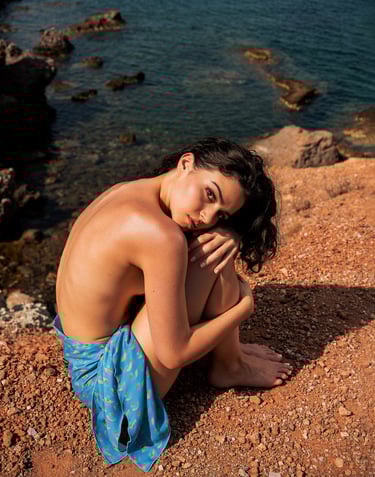a woman sitting on a rock in front of a body of water