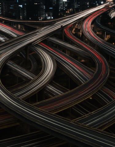 A high-altitude drone photograph of a complex highway interchange in an East Asian / Korean urban center at night. Car headlights create long white and red light trails against deep charcoal asphalt.