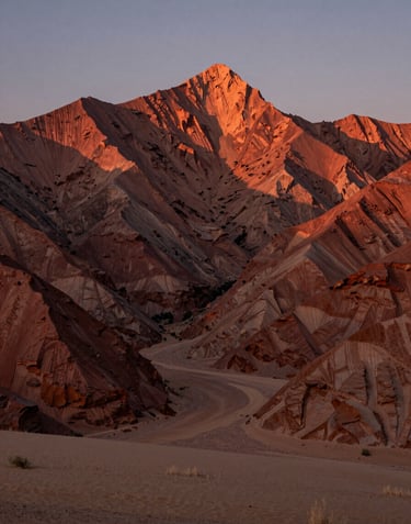 A cinematic landscape of a North American / US mountain range at dusk. Warm terracotta light hitting the peaks, soft sand valley below.
