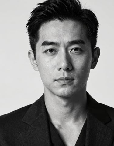 A striking black and white portrait of a professional actor in a dark suit. High contrast lighting using #F5F5F5 and #0F0F0F. Sharp focus on the eyes, cinematic grain, minimalist background. The composition is elegant and authoritative.