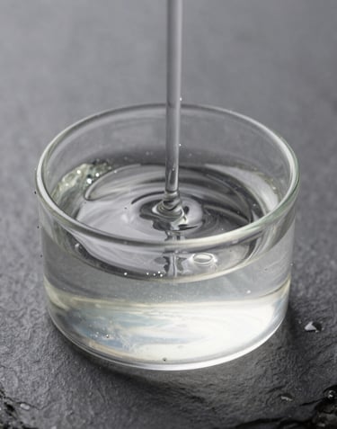 Macro photography of clear, high-quality liquid fuel shimmering in a transparent container against a minimalist slate background, studio lighting, clean and professional.
