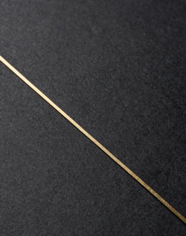 A close-up photograph of thick, high-quality charcoal paper with a subtle gold embossed line. Minimalist, tactile, and representing exclusive intellectual control.