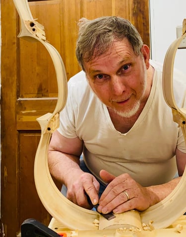 Jim Clinton peering with a smile, through a cello rib skeleton
