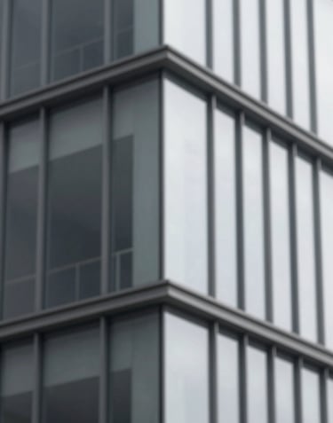 A close-up detail of a minimalist building corner showing the intersection of glass and steel, with a refined aesthetic using tones of #F7F9FB and #262F38.