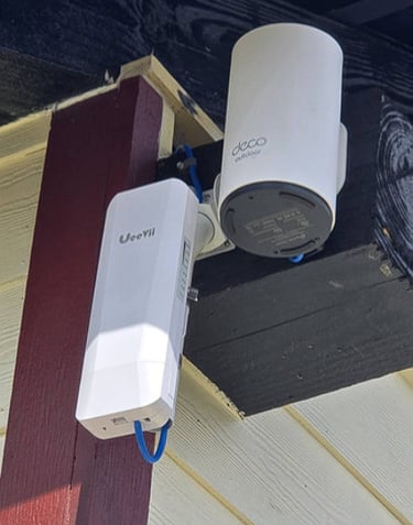 TP-Link Deco outdoor mesh WiFi node and UeeVii wireless bridge mounted on a house exterior.