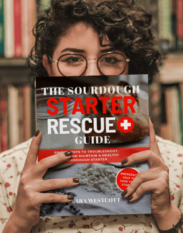woman holding book the sourdough starter rescue guide