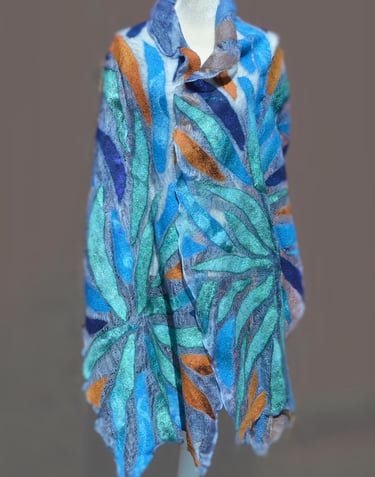 Handmade nuno felted scarf with blue, teal, and orange leaf patterns on a blue silk background.