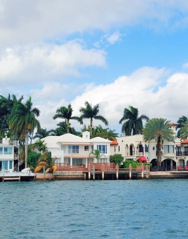 Luxury waterfront real estate featuring tropical villas and palm trees along a Florida canal.