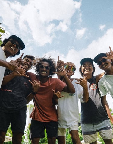 The team giving shaka signs against a bright blue sky.