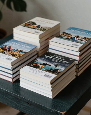 An organized display of professional travel books with ISBN barcodes visible, stacked neatly on a dark charcoal green wooden table with a soft sage leaf in the background.
