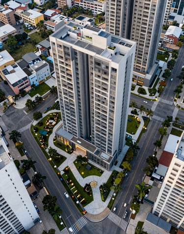 A bird's-eye view of a modern urban residential project in South America / Ecuador. Sleek buildings surrounded by green areas and high security gates, luxury communal spaces, bright daytime lighting.