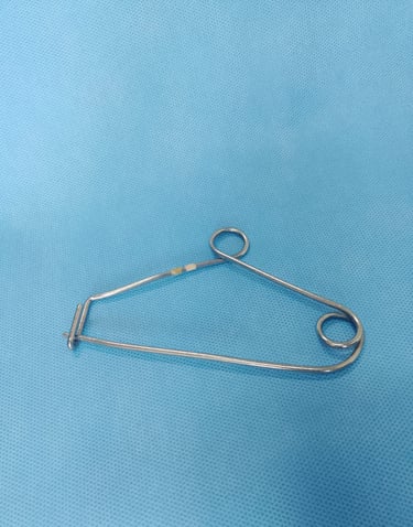 Clipe de Mayo sobre tecido azul estéril, usado para organizar pinças cirúrgicas na mesa de instrumen