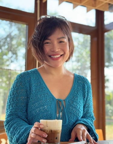 Tina in a blue sweater is smiling and holding a coffee