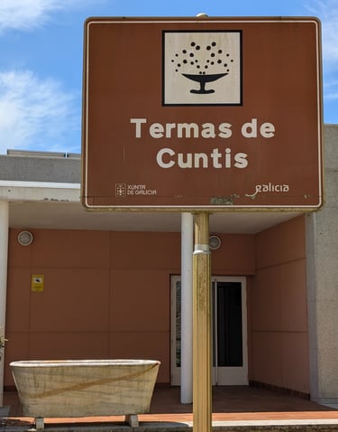 a sign that says Termas de Cunits with a marble bathtub next to it