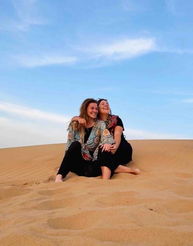 Eva et Manon assises dans le désert de Jaisalmer, entourées de dunes dorées au coucher du soleil.