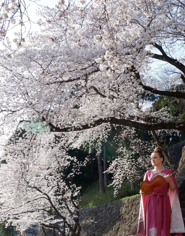 Violinist standing under a blooming cherry blossom tree, wearing a pink kimono remake dress and holding a violin in Japan