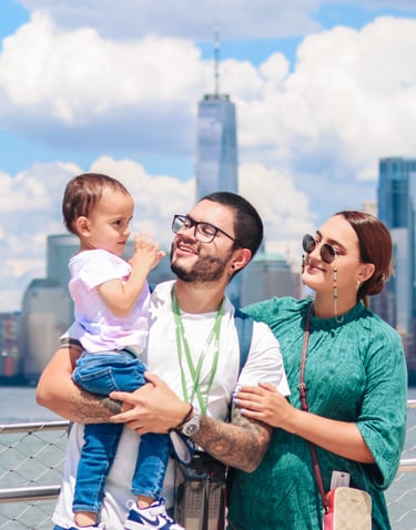 Happy family with toddler posing in front of the One World Trade Center and New York City skyline.