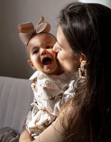 mother holding her baby on the arms and kissing baby's cheek